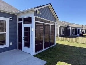 Back porch screen enclosure with white trim, dark mesh screen panels, transom windows, and a white screen door on a concrete patio