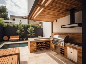 Covered outdoor kitchen with wood pergola, stainless steel grill, wood slat cabinets, and stone paver patio